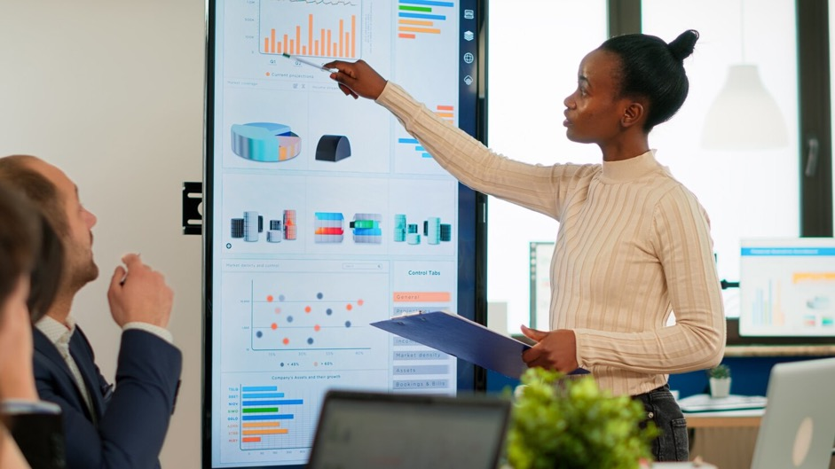 A group of marketing professionals reviewing performance metrics on a large digital dashboard in a modern office setting